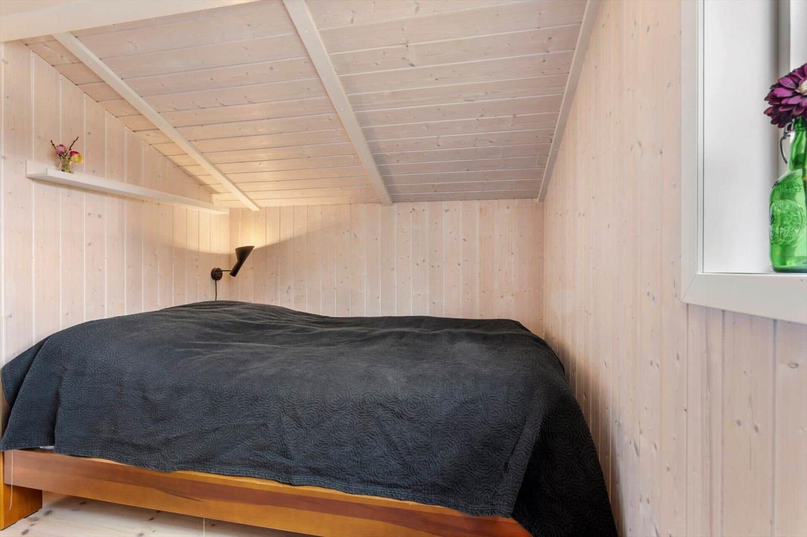 Schlafzimmer mit Holzwand und Bett unter Dachschräge