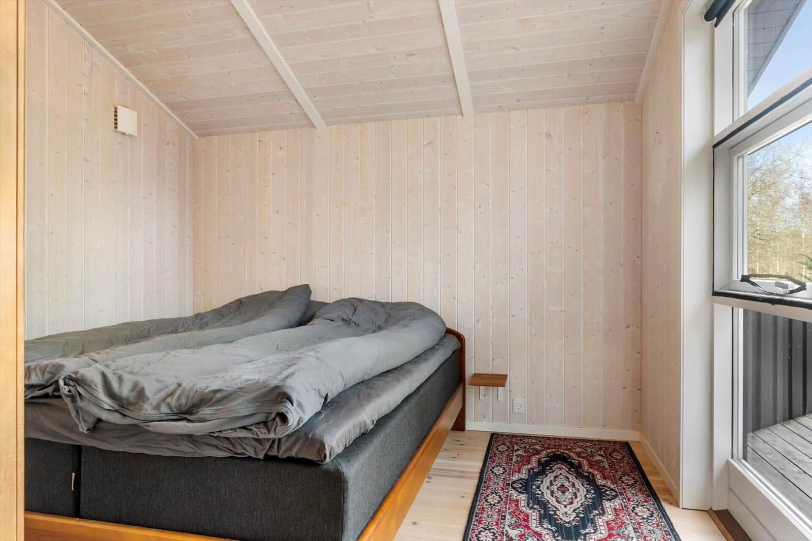 Schlafzimmer mit Holzwänden, Bett und Fenster