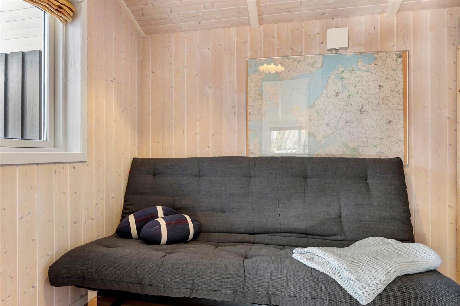 Graße Schlafcouch mit Kissen und Decke an Holzwand unter Karte.