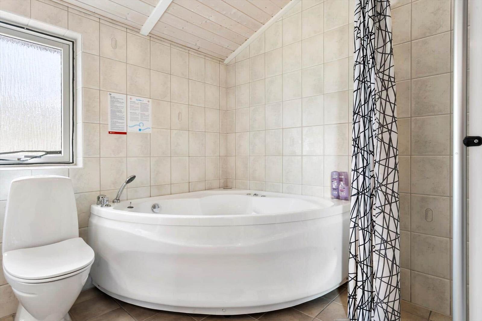 Bad mit Whirlpool, Toilette und Fenster mit beschichtetem Glas.