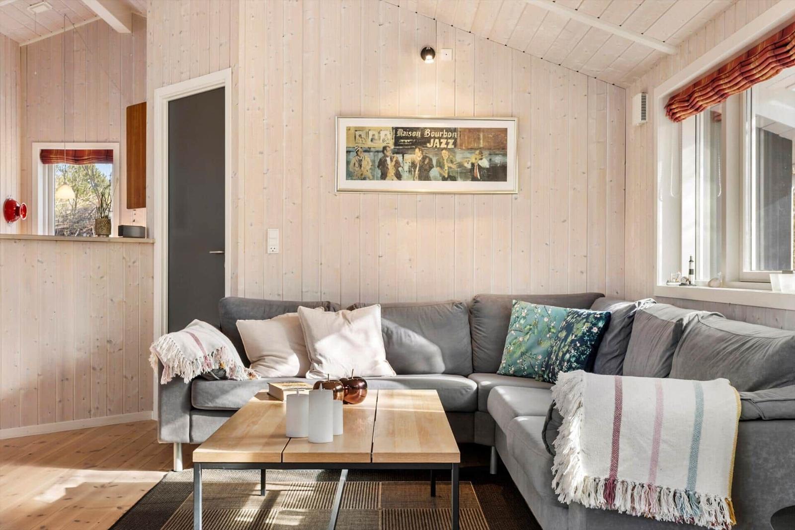 Ein Wohnzimmer mit grauem Sofa, Holztisch und Holzwänden.