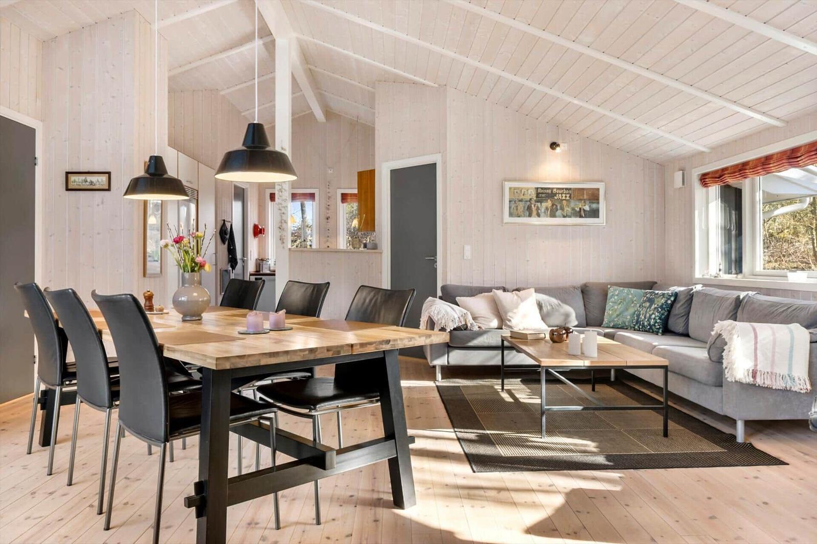 Wohn- und Essbereich mit Holzdecke, Sofa und Esstisch.