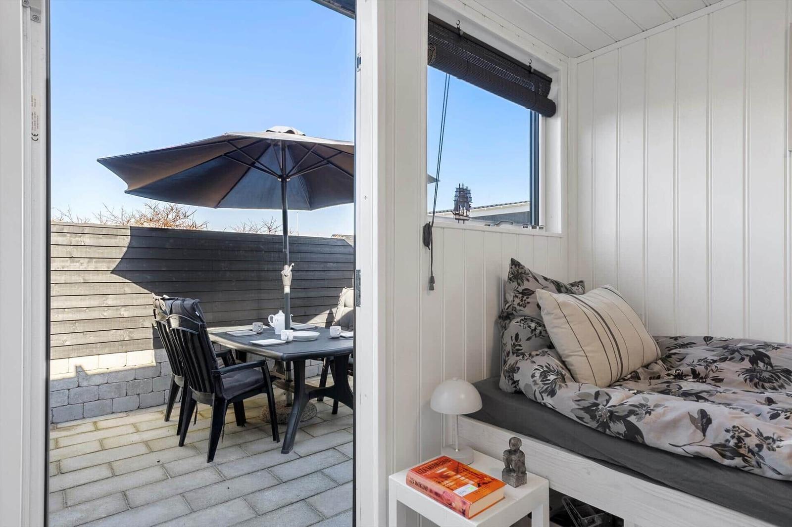 Ein Schlafzimmer mit Blick auf eine Terrasse mit Tisch, Stühlen und Sonnenschirm.