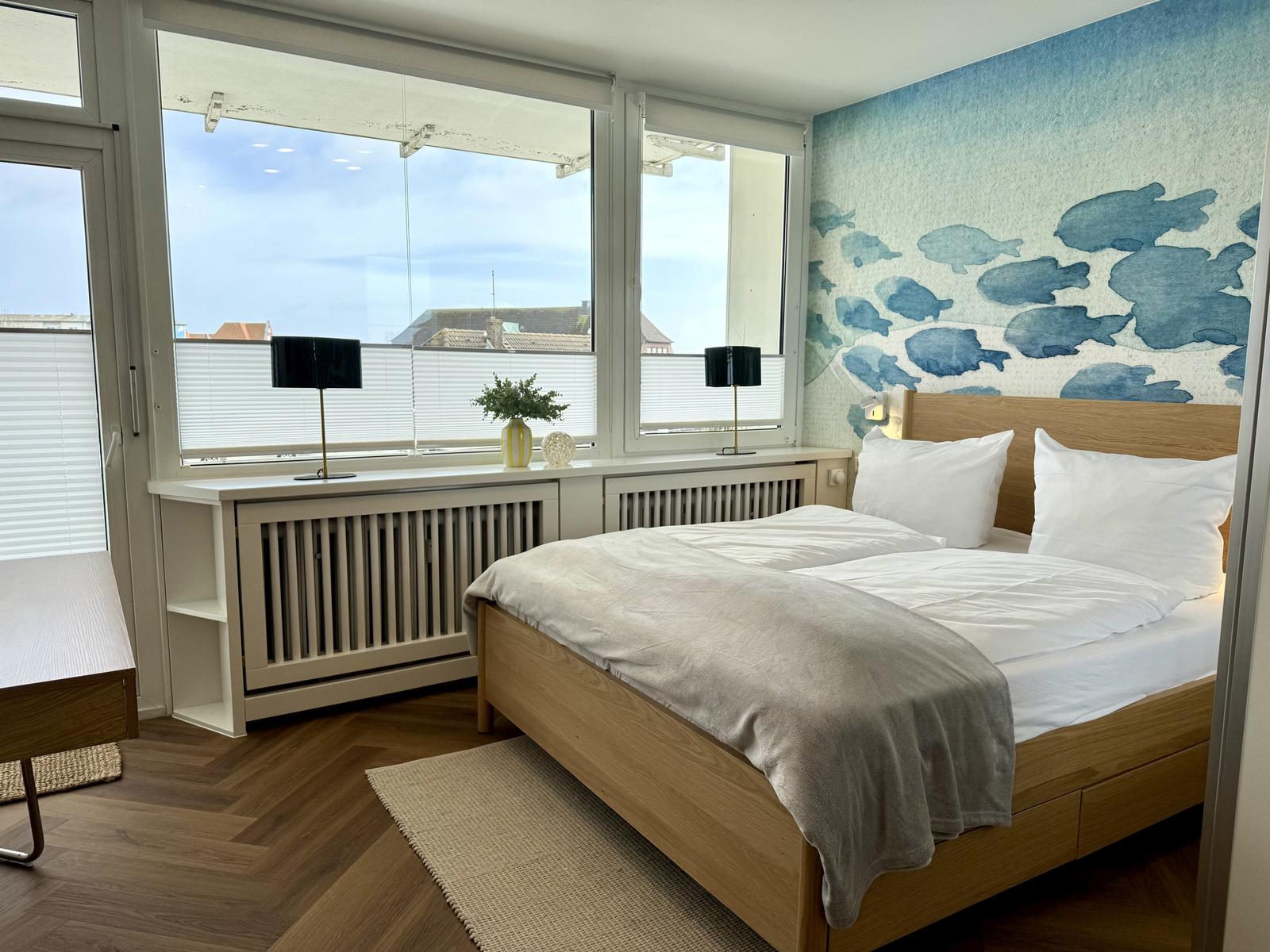 Schlafzimmer mit Bett, Fenster und Wand mit Fischmotiv.