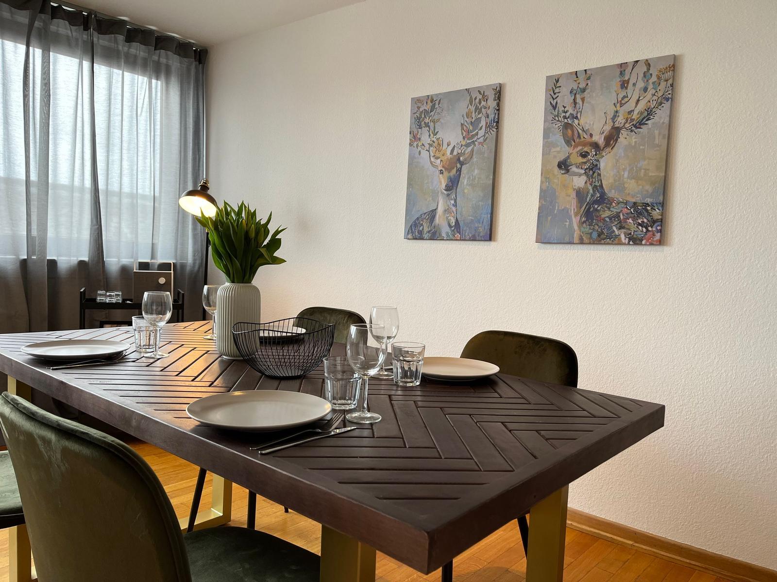 Esstisch mit Stühlen, Wandbildern und Pflanze