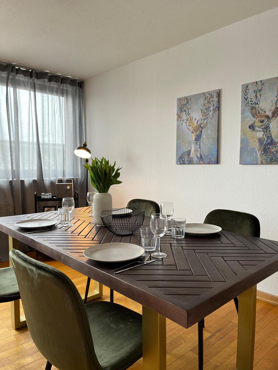 Esszimmer mit Tisch, Stühlen und Wandbildern von Hirschen.