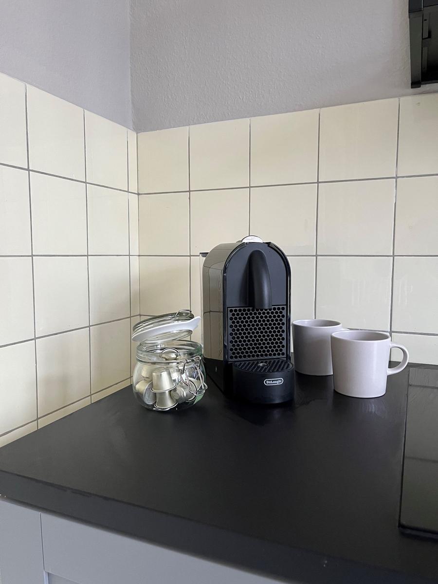 Kaffeemaschine mit Kapseln und Tassen auf Küchenarbeitsfläche