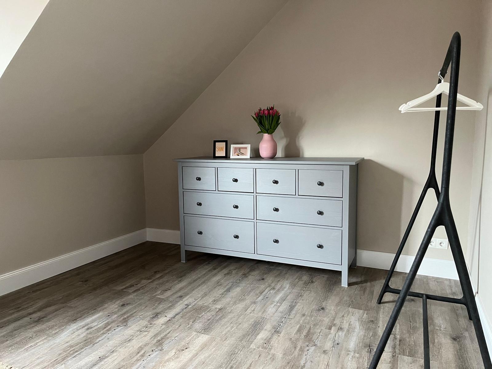 Schlafzimmer mit grauem Schrank, Blumen und Kleiderständer