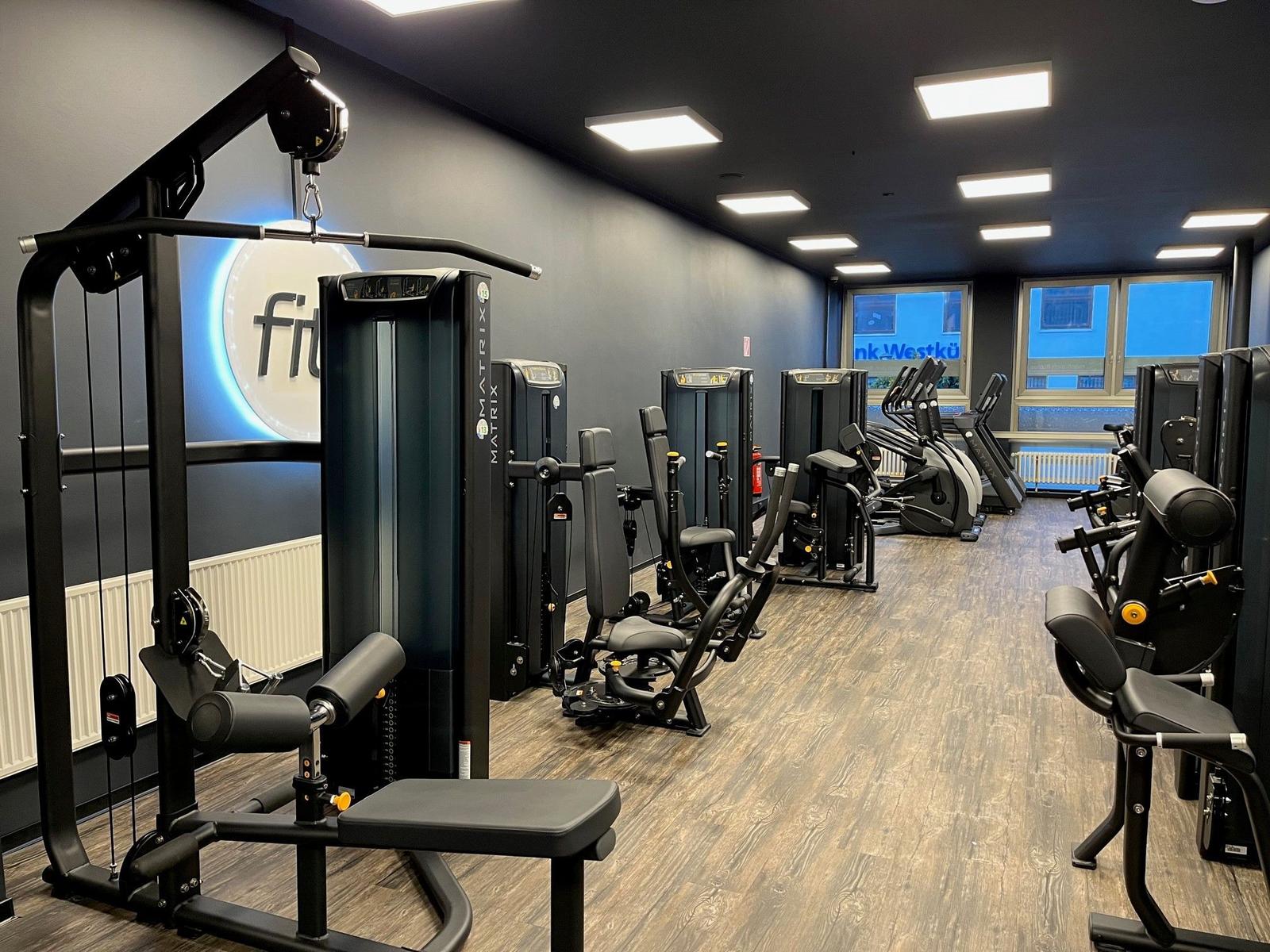 Fitnessraum mit Matrix-Geräten und Holzboden
