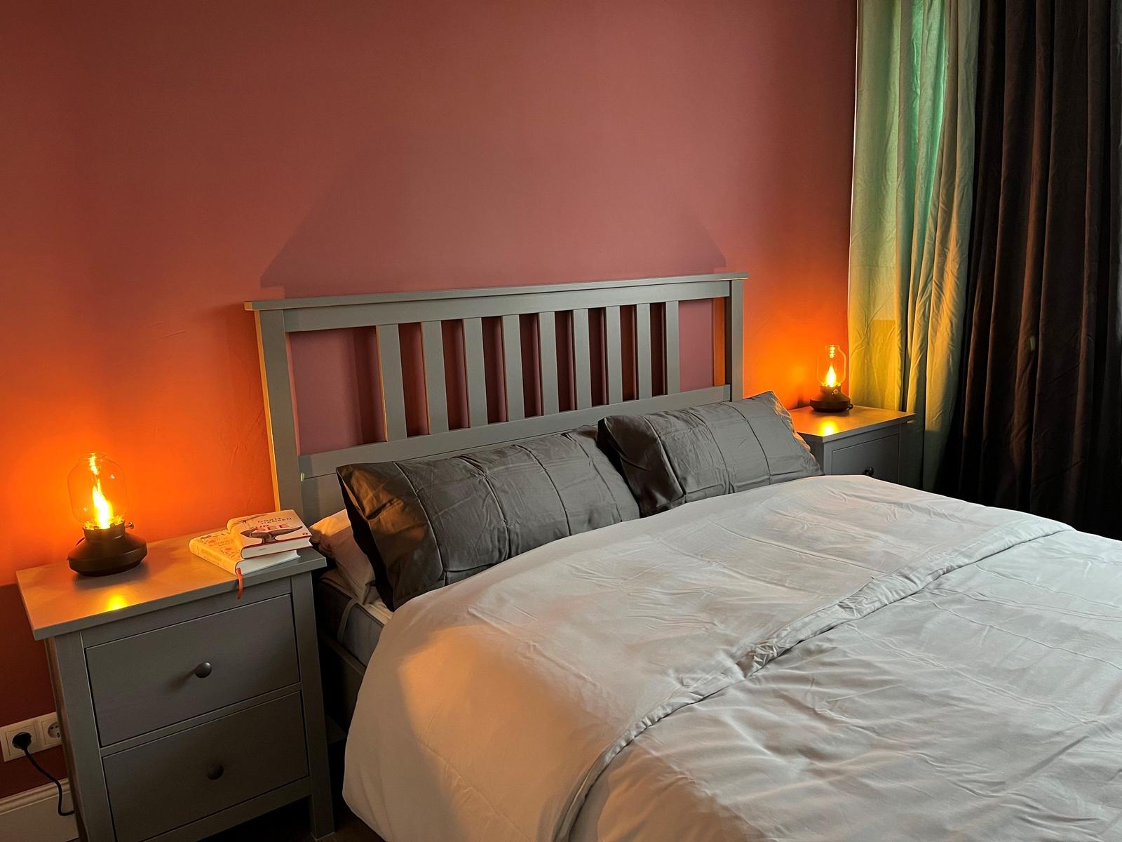 Schlafzimmer mit Bett, Nachttisch und Lampe an der Wand.