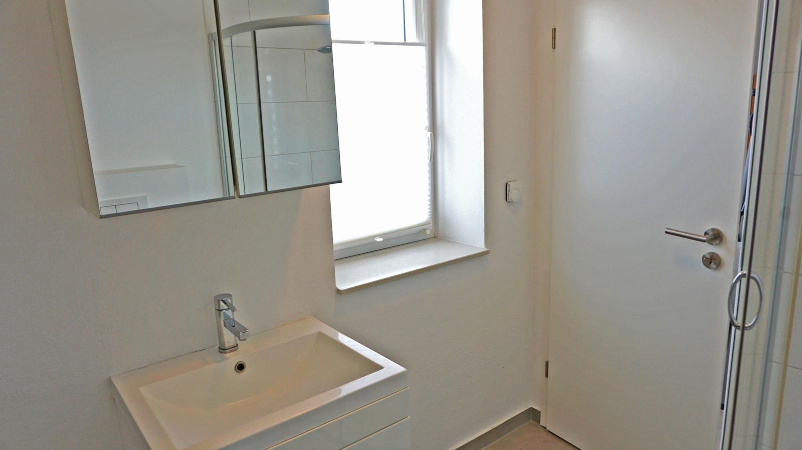 Badezimmer mit Waschbecken, Spiegel und Dusche