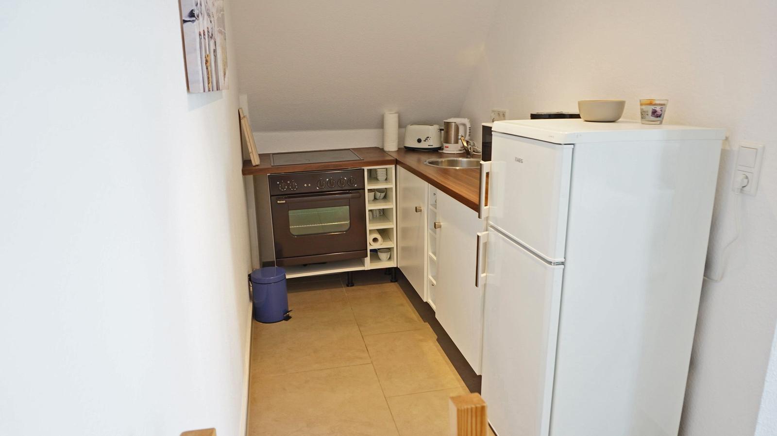 Küche mit Kühlschrank, Herd und Spüle.