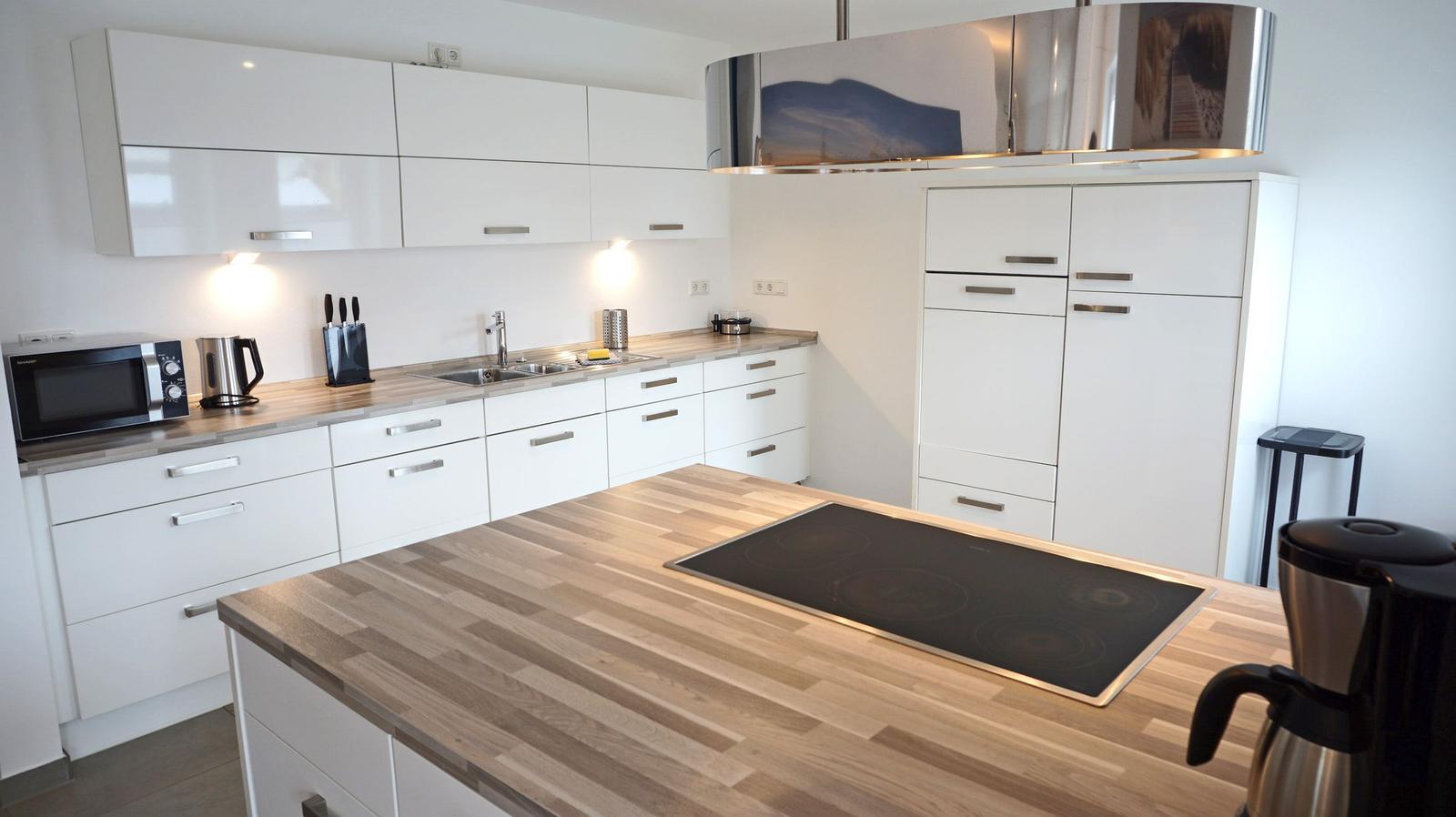 Moderne Küche mit weißen Schränken, Holzoberfläche und Edelstahlherd.