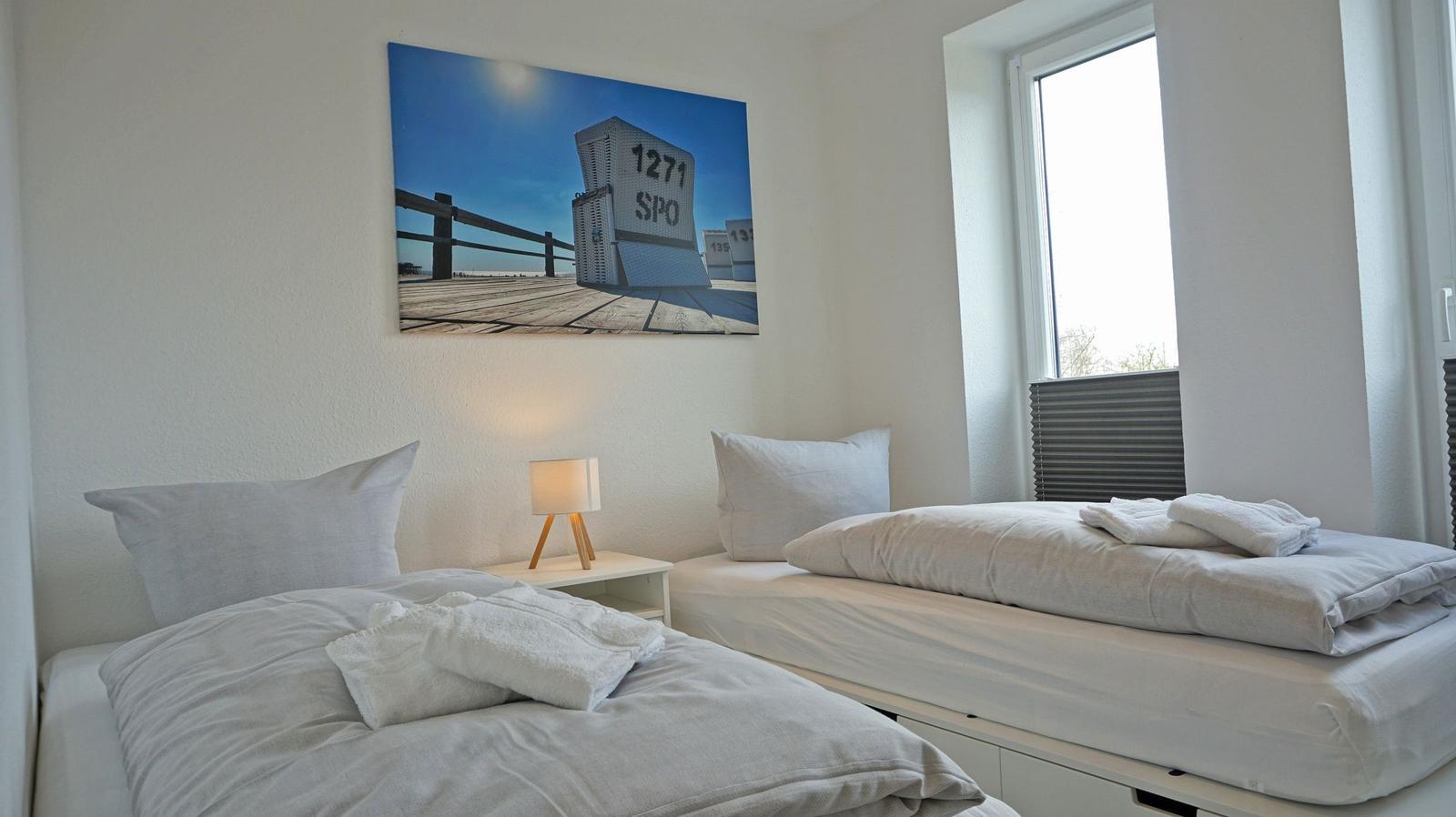 Zwei Betten mit weißen Bettwäschen und einem Wandbild über dem Kopfteil.