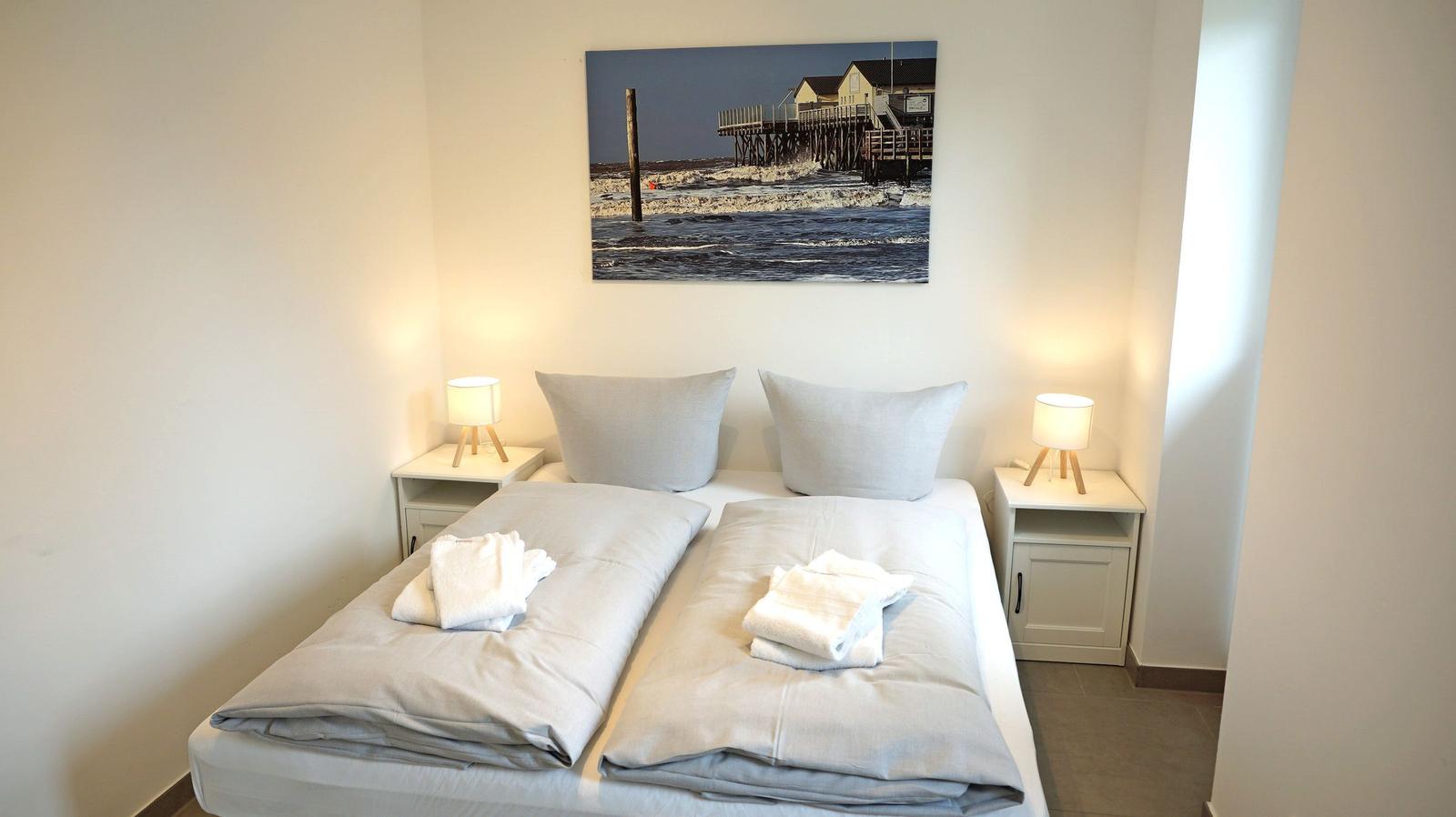 Zimmer mit Doppelbett, zwei Nachttischen und Wandbild an der Wand.