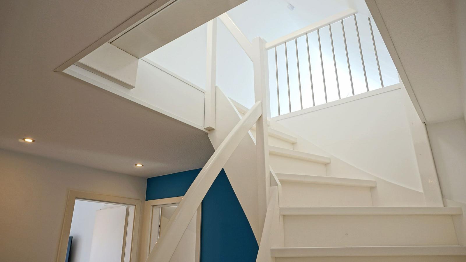 Treppenhaus mit weißer Treppe und Dachfenster