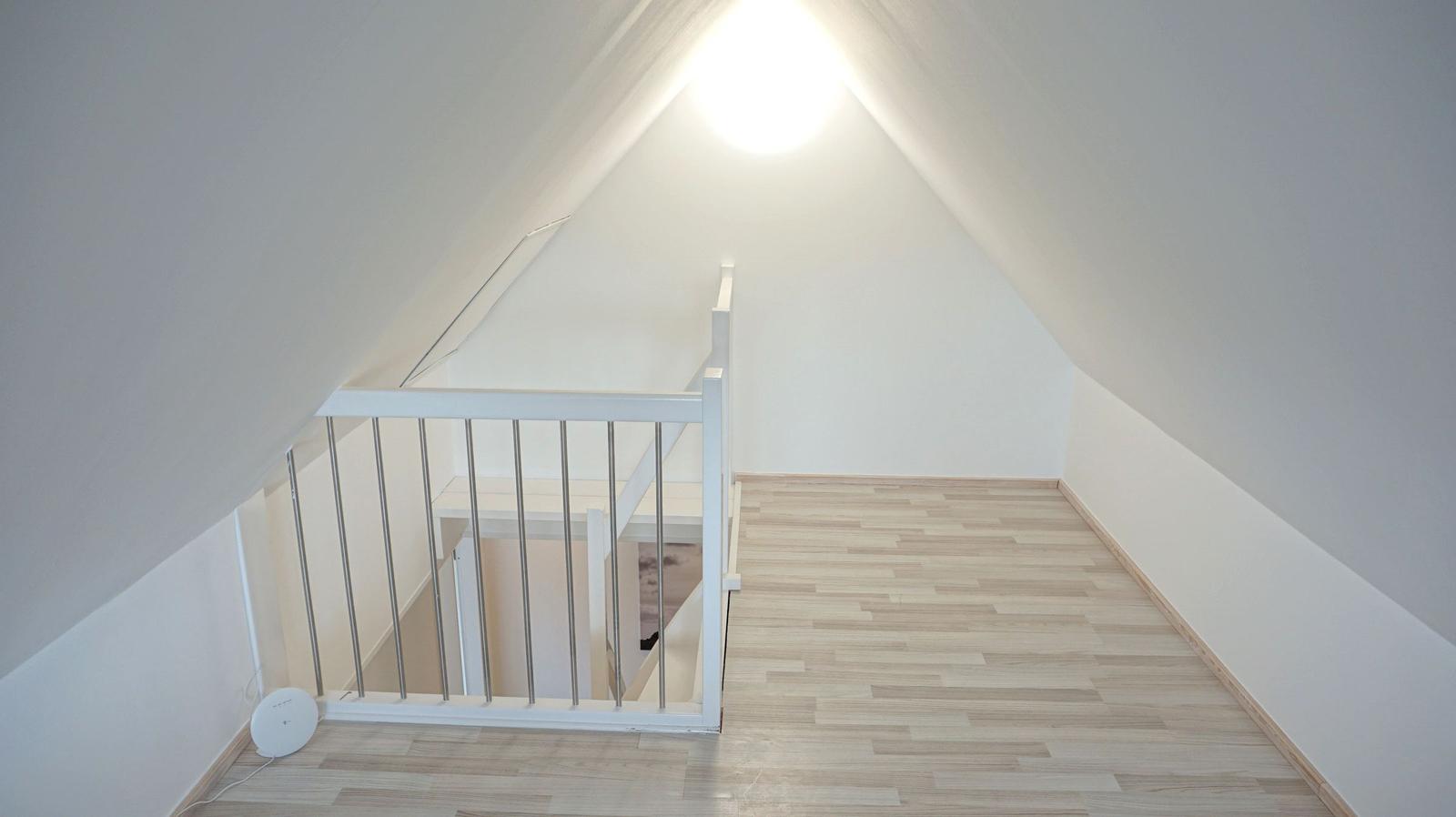 Dachgeschoss mit Holzboden und weißer Brüstung unter schrägen Wänden