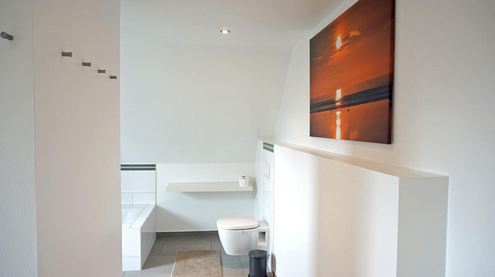 Badezimmer mit Toilette, Badewanne und Wandbild