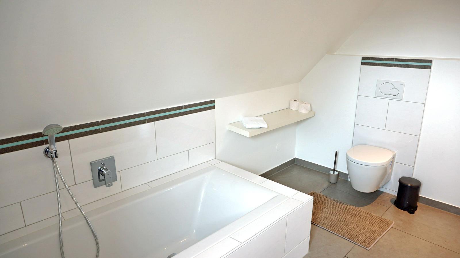Bad mit Badewanne, Toilette und Regal an der Wand.