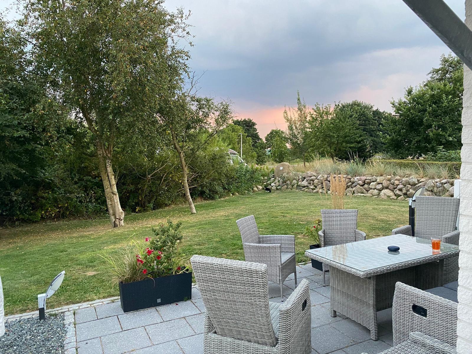 Terrasse mit Sitzgruppe, Garten und Blick auf Wald.
