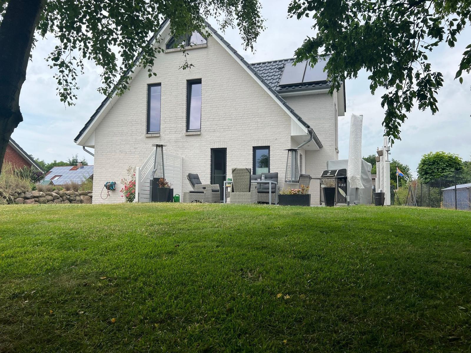 Modernes Haus mit großem Garten und Außensitzgelegenheit.