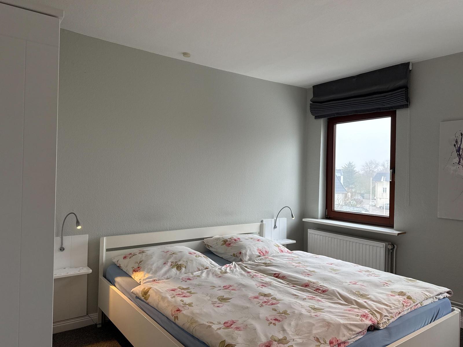 Bedroom with bed, nightstands, and window. Bed with floral bedding.