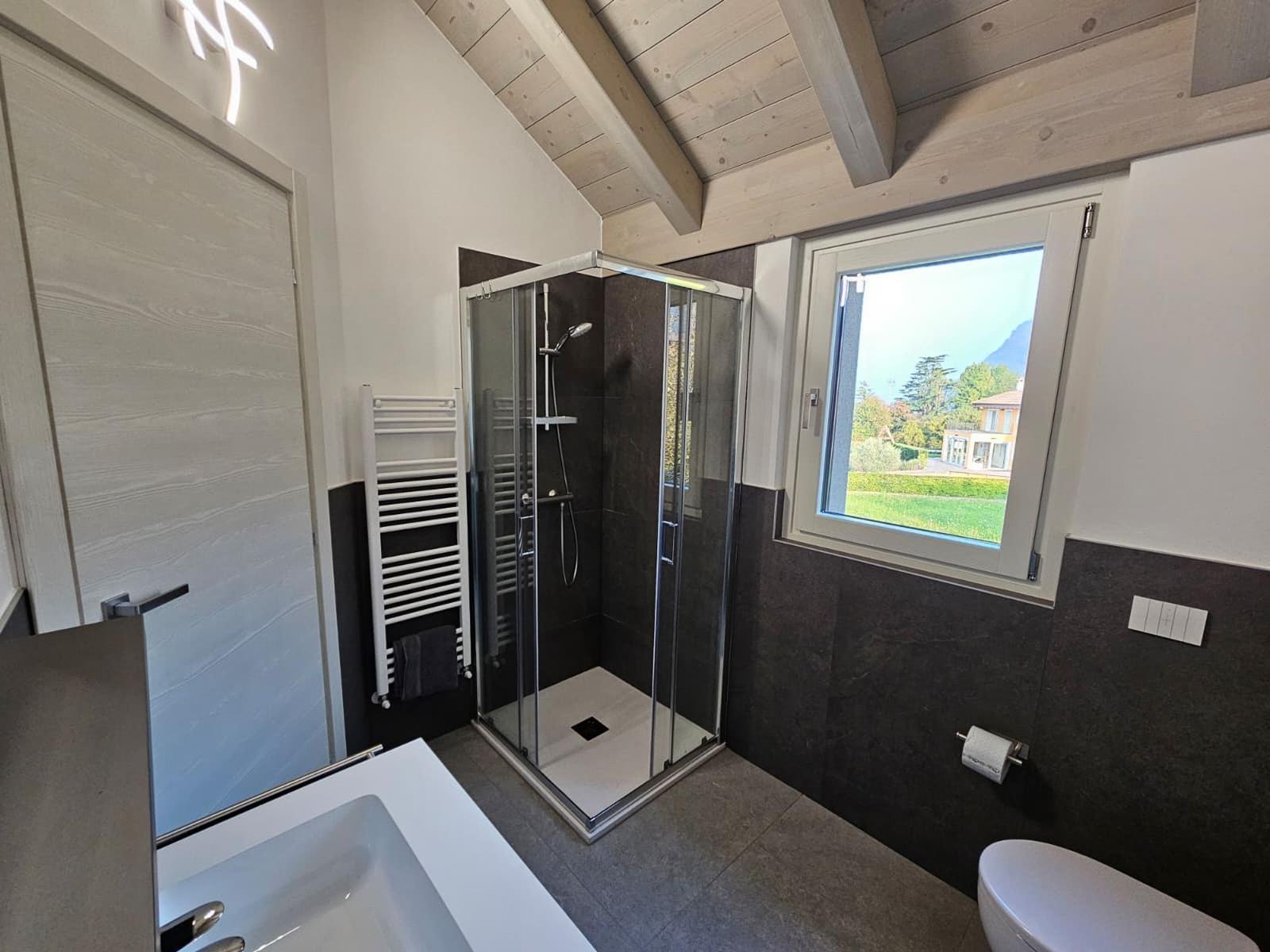 Badezimmer mit Dusche, Badewanne und Fensterblick