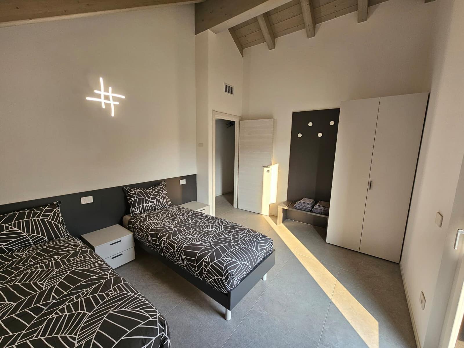 Zimmer mit zwei Betten, Kleiderschrank und Deckenbeleuchtung.