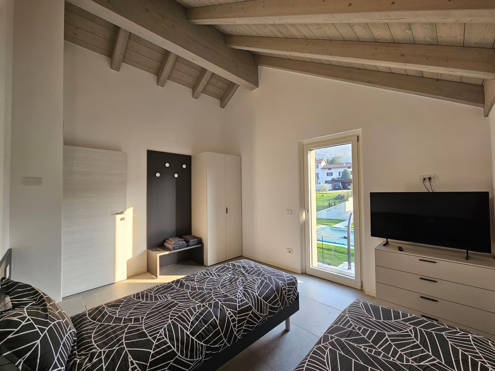 Zimmer mit zwei Betten, TV und Blick auf Pool.