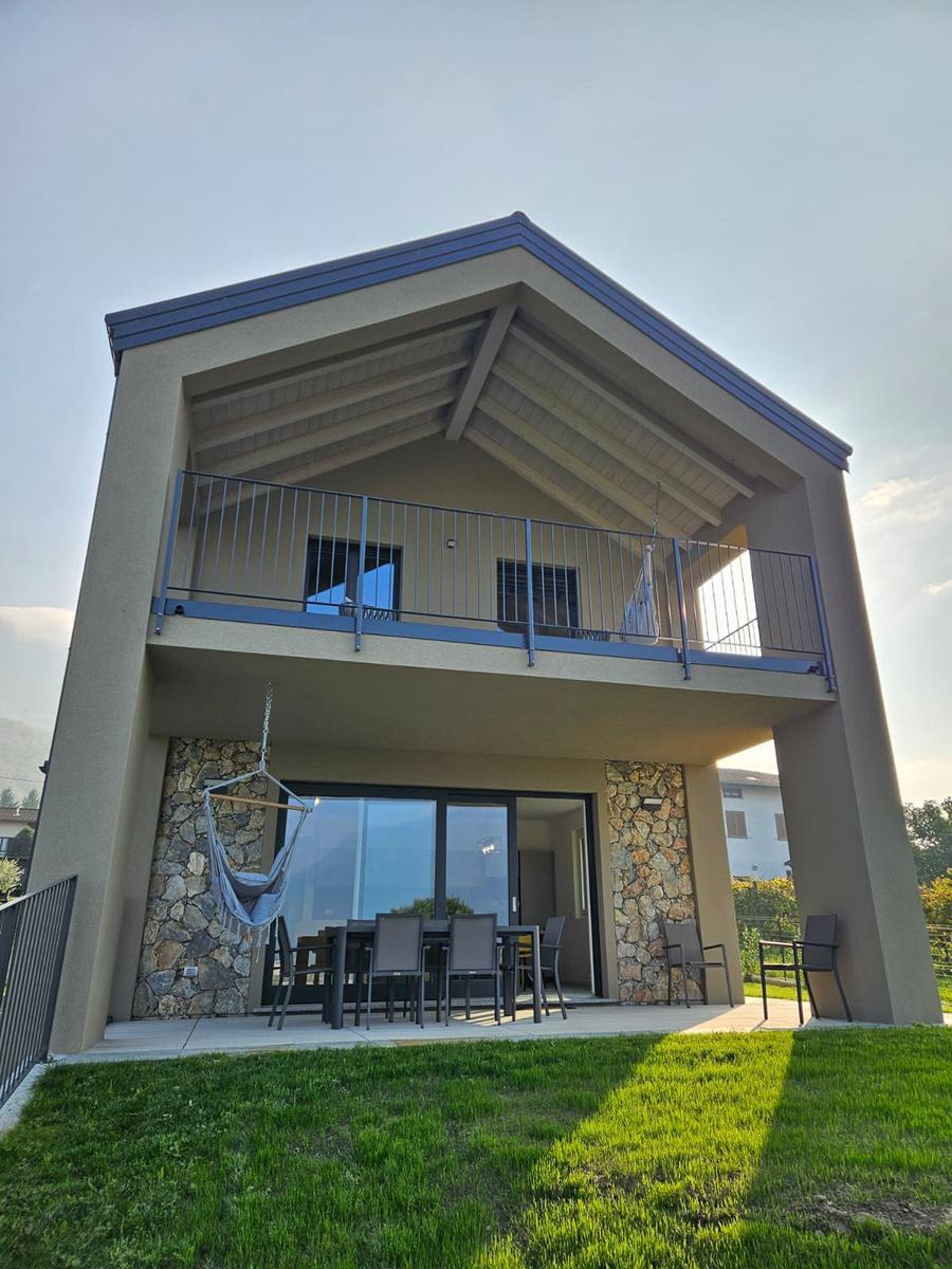 Moderne Villa mit Balkon, Terrasse und Hängematten. Steinmauern und großes Fenster.