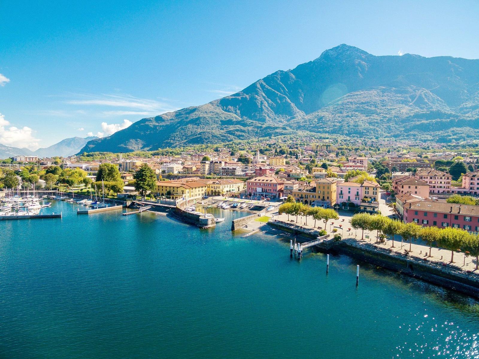 Hafenstadt mit Booten, Bergen und bunten Häusern am See.