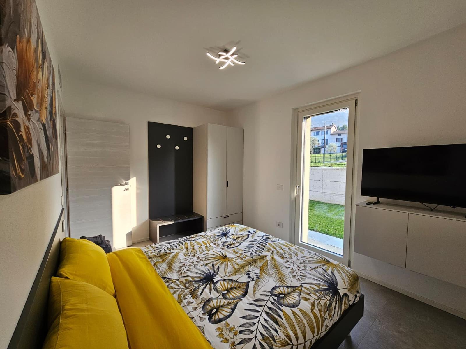 Schlafzimmer mit Bett, TV und Fenster zum Garten.