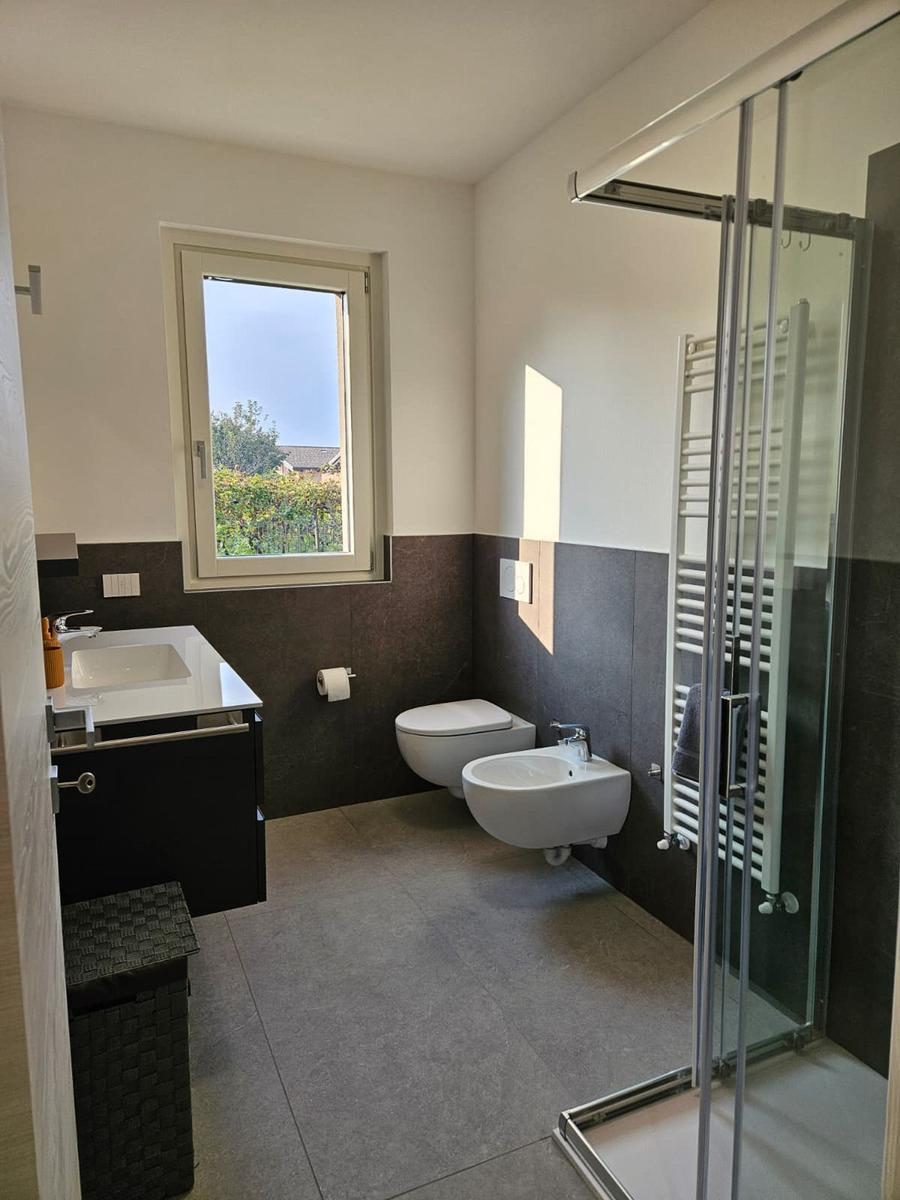 Badezimmer mit Dusche, Waschbecken und Toilette. Fenster mit Blick auf Garten.
