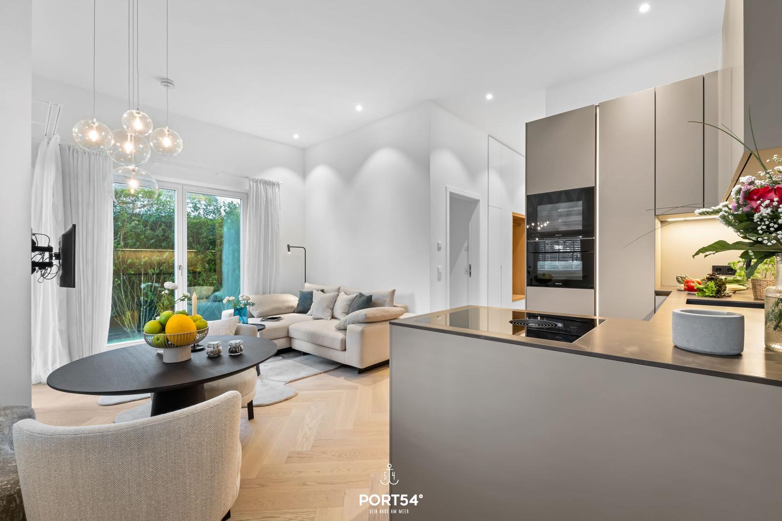 Modern eingerichteter Wohn- und Essbereich mit Kücheninsel und großem Fenster.