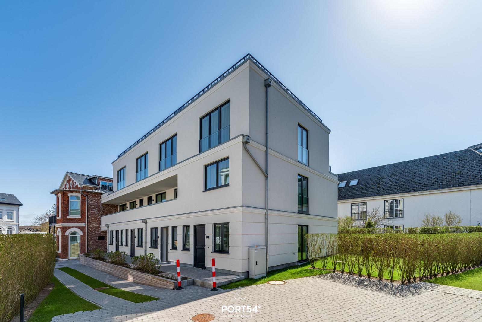 Moderne, mehrstöckige Villa mit Balkonen und gepflegtem Garten.