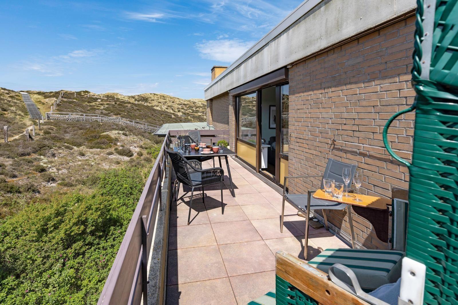 Terrasse mit Tisch, Stühlen und Blick auf Dünen