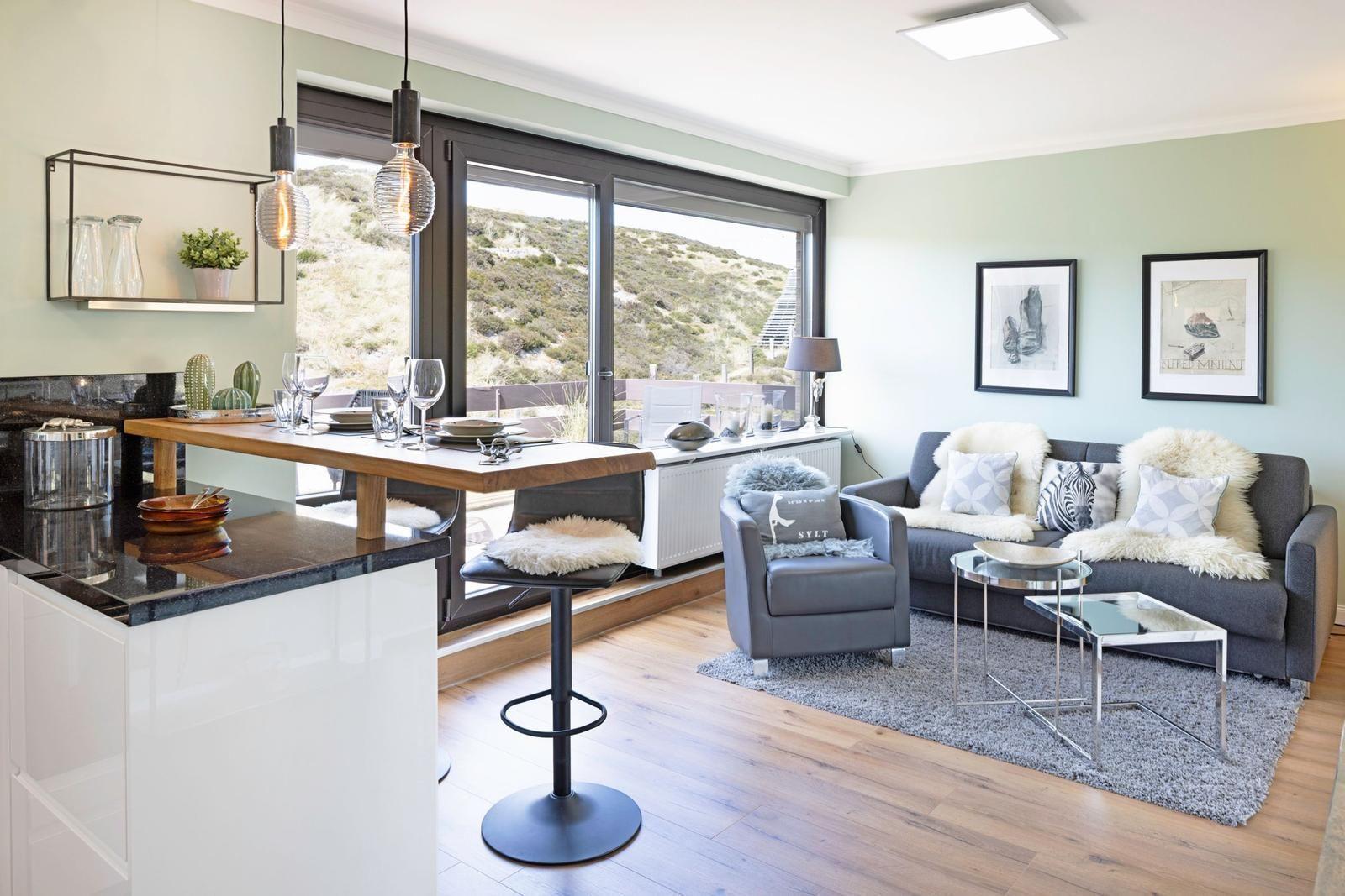 Moderne Küche mit Sitzgelegenheit und Wohnbereich mit Sofa und Sessel.