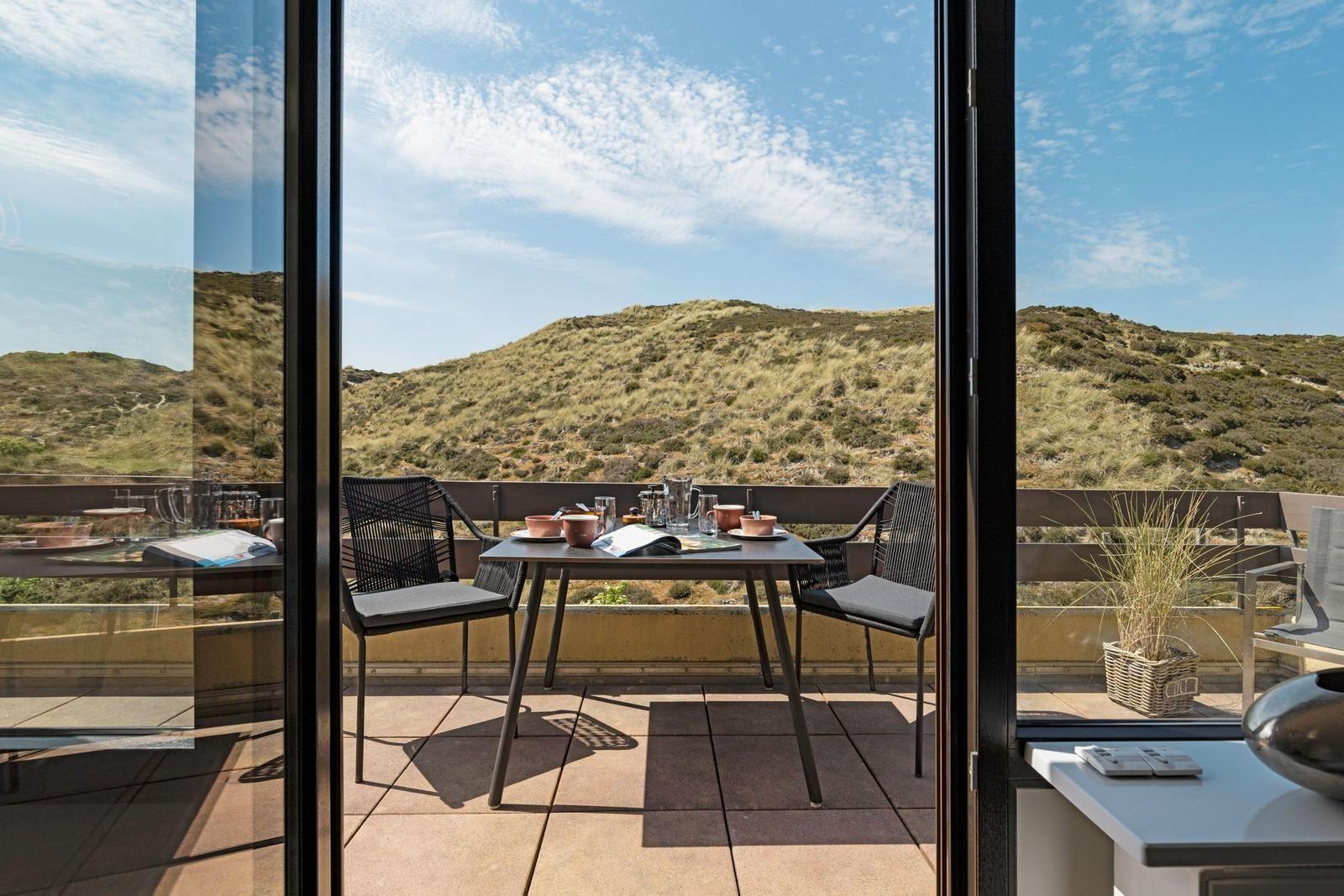 Terrasse mit Tisch und Stühlen bietet Aussicht auf Hügel.