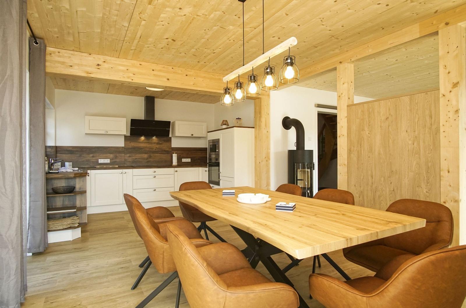 Essbereich mit Holztisch und Ledersitzen. Küche und Kamin im Hintergrund.