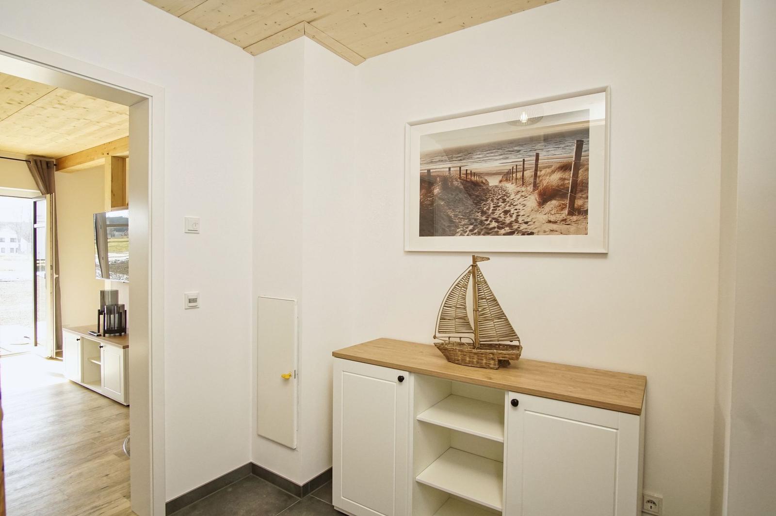 Eingangsbereich mit Schrank, Wandbild und Segelbootmodell.