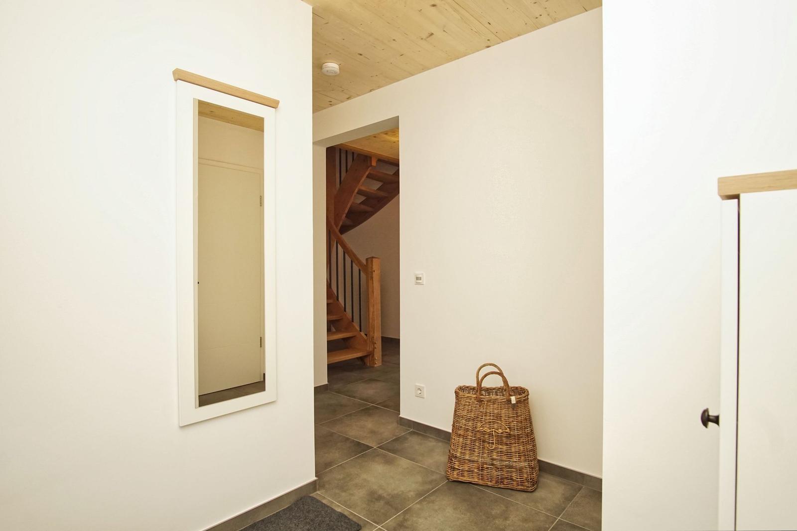 Eingangsbereich mit Spiegel, Holztreppe und Korb.