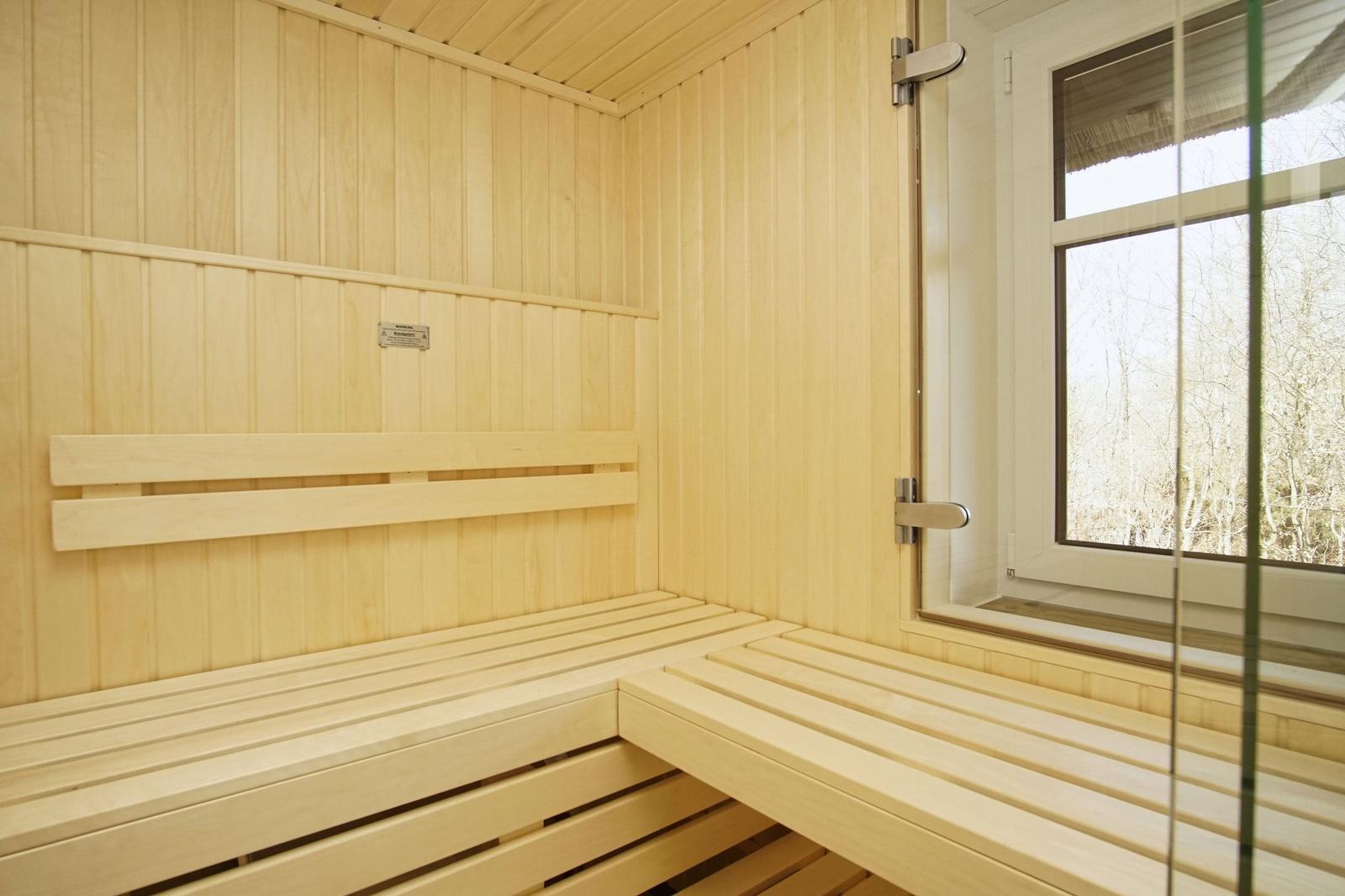 Holzsauna mit Sitzbänken und Fenster zur Aussicht.
