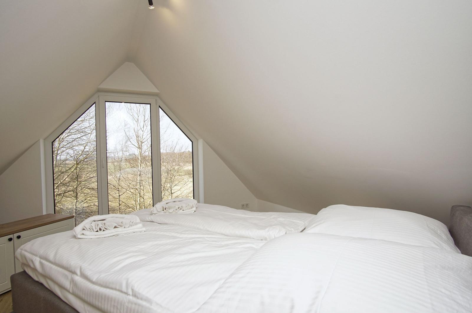 Schlafzimmer mit Doppelbett und großem Fenster zum Blick auf die Landschaft.