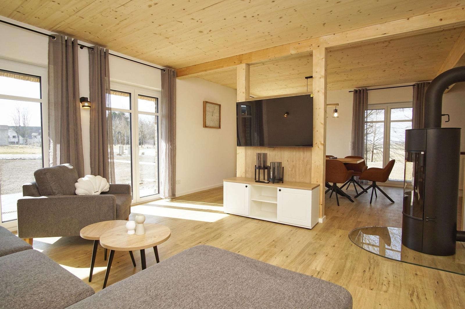 Wohnzimmer mit Holzdecke, Sofa, Fernseher und Kaminofen.