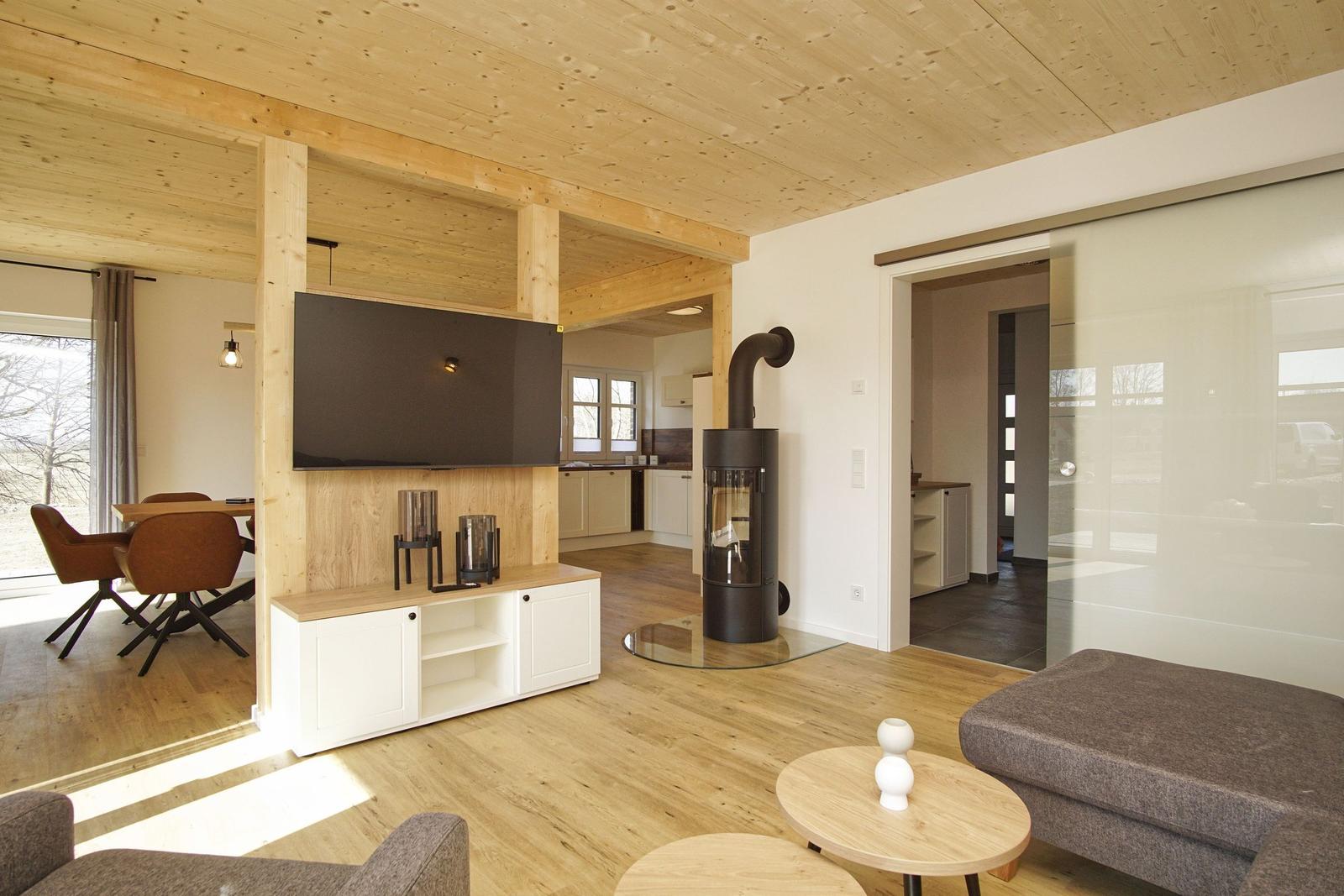 Wohnbereich mit Holzdecke, Kamin und TV. Durchgang zur Küche und Schlafzimmer.