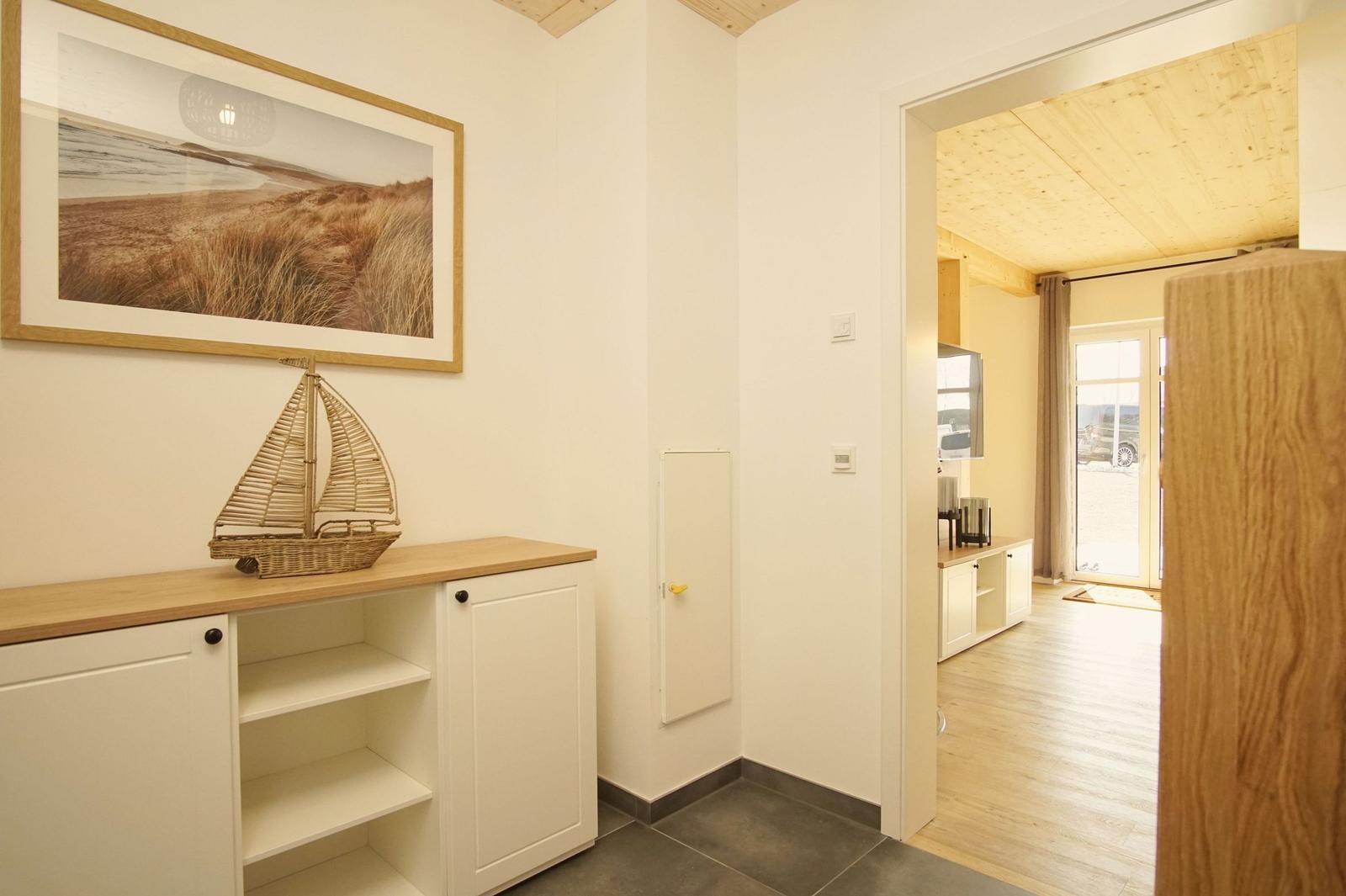 Eingangsbereich mit Schrank, Wandbild und Blick in Wohnbereich.