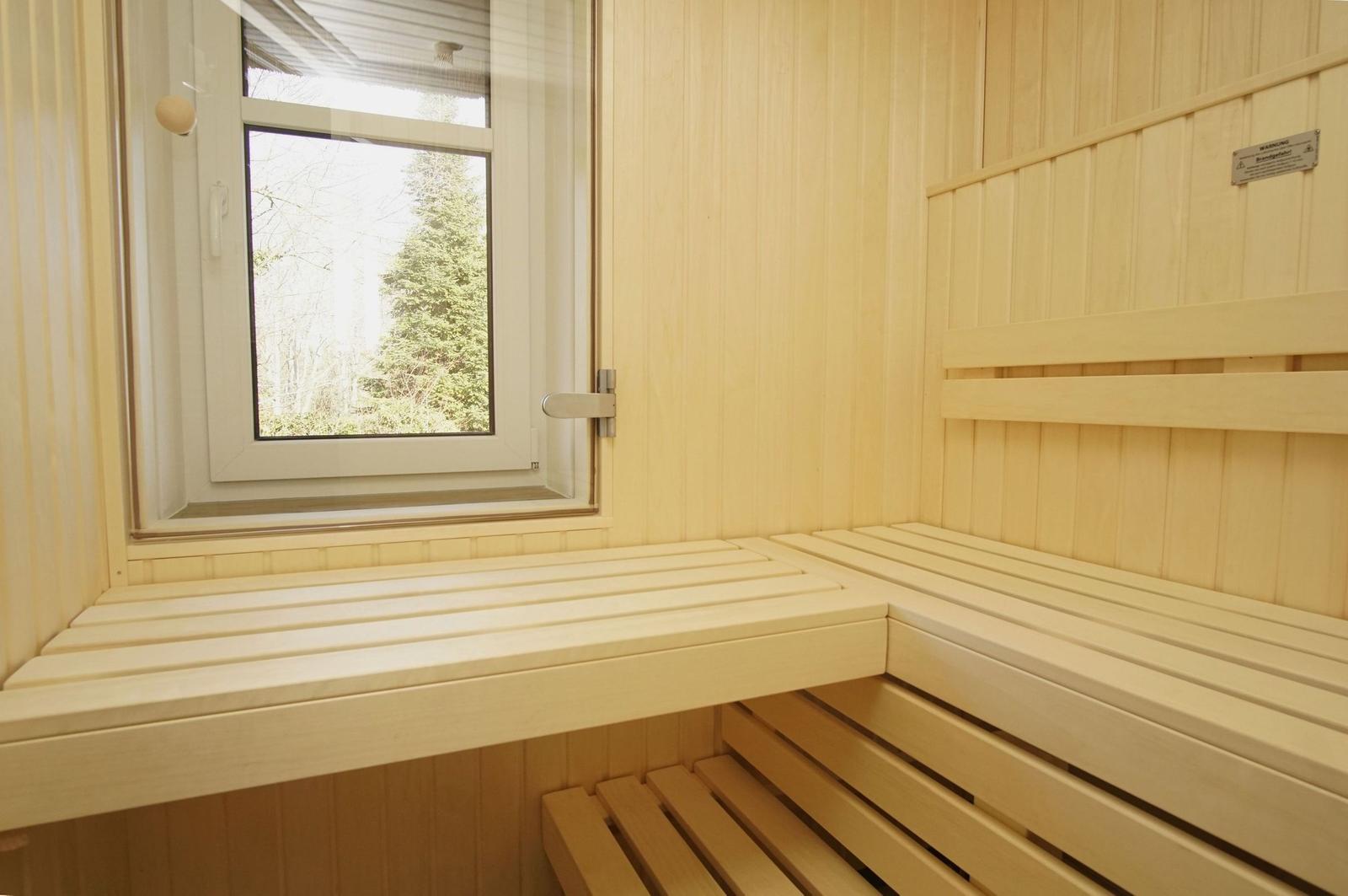 Sauna mit Holzbänken und Fensterblick auf Wald