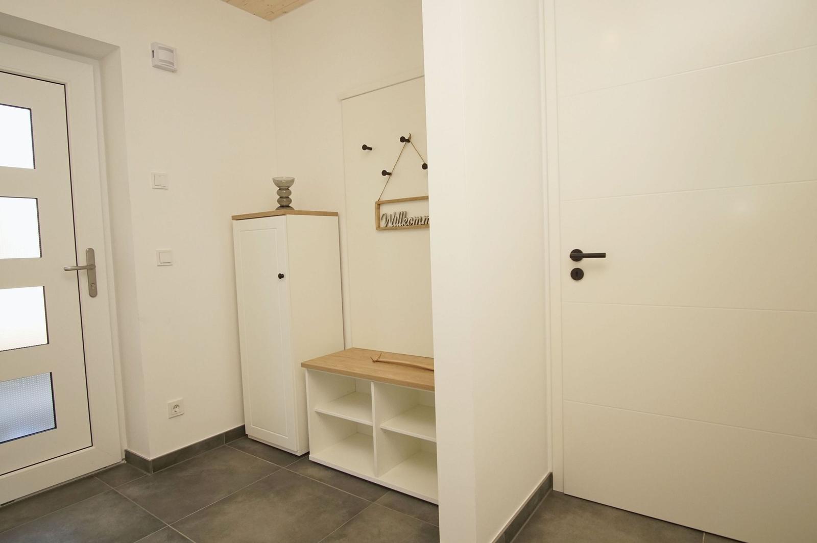 Eingangsbereich mit Schuhschrank und Willkommensschild