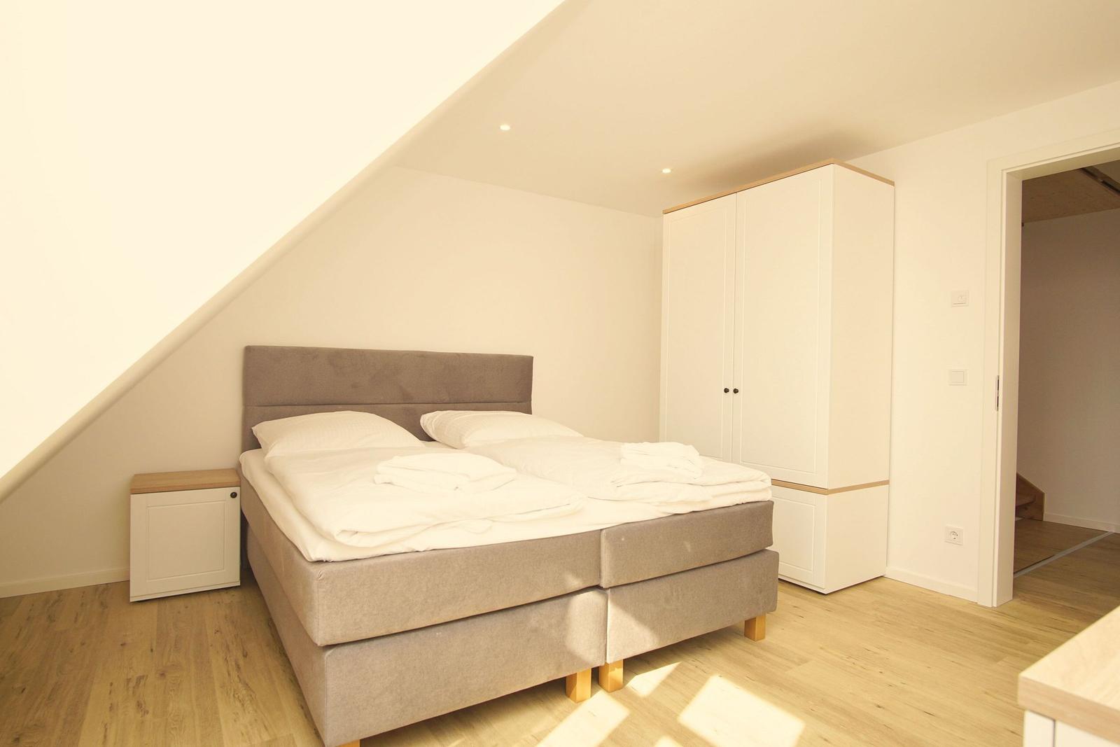Schlafzimmer mit Doppelbett, Kleiderschrank und Holzboden.