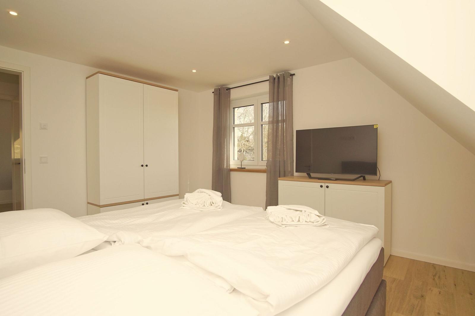 Schlafzimmer mit Doppelbett, Kleiderschrank und Fernseher